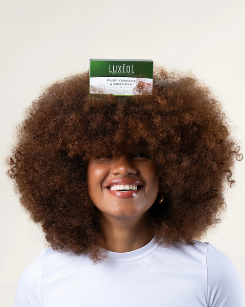 Person with an afro wearing a Luxeol product on their head against a plain background