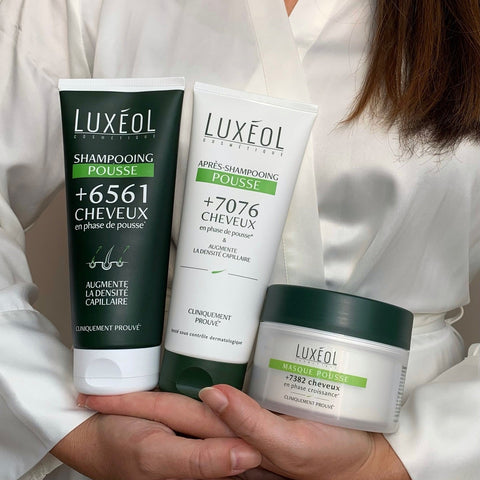 Person holding Luxéol hair care products in a white robe