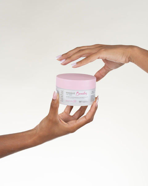 Kaks kätt hoiavad roosa ja valge purki neutraalses taustas