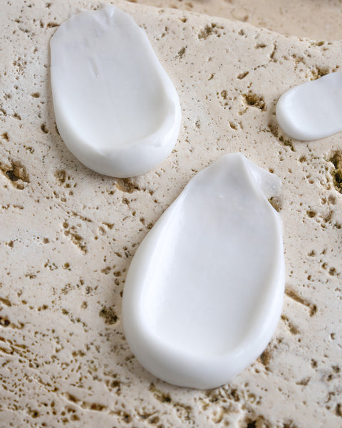 Three white teardrop-shaped objects on a textured beige surface
