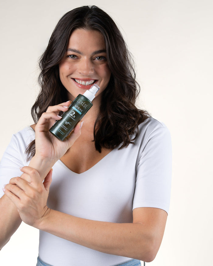 Woman holding a spray bottle with a white background